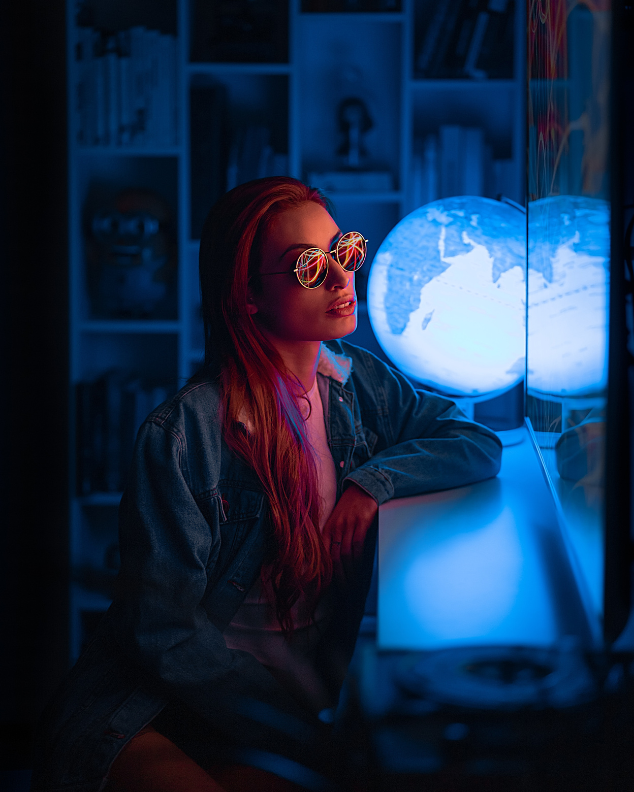 a person with red hair sitting in front of a globe