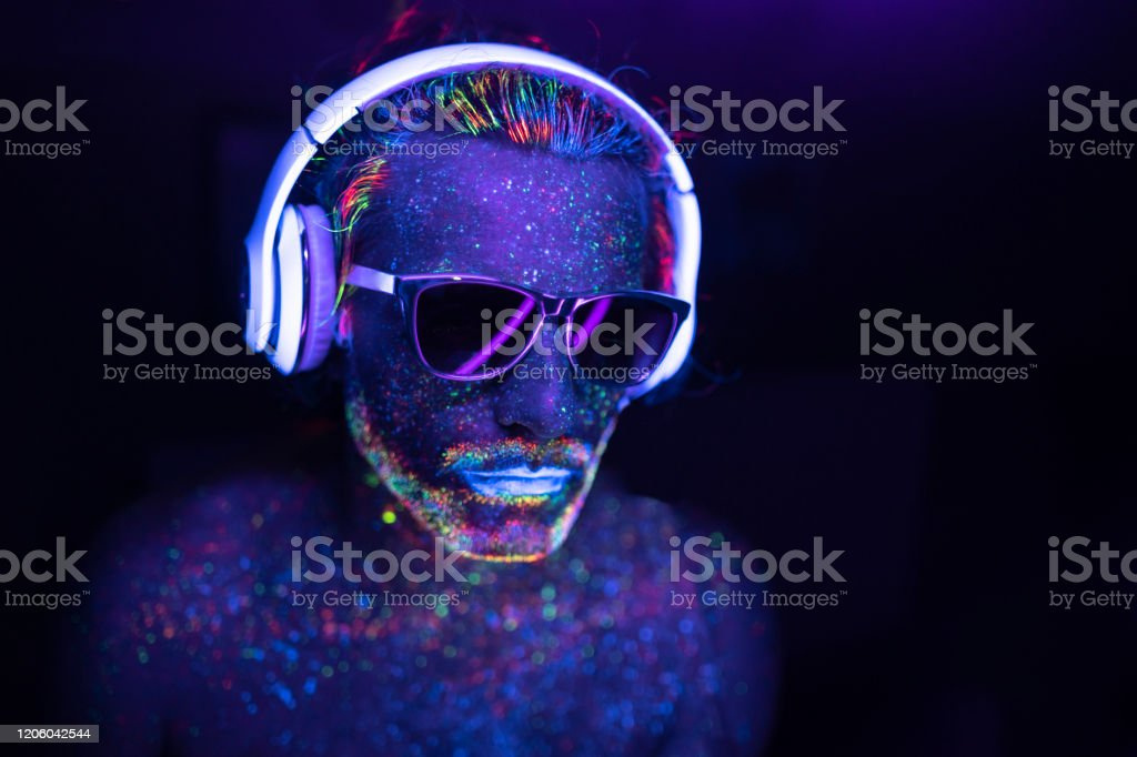 a person with glow in the dark paint on their face and headphones stock photo